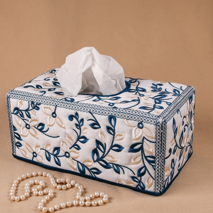 A rectangular tissue box cover with a floral machine embroidery design in blue and beige.