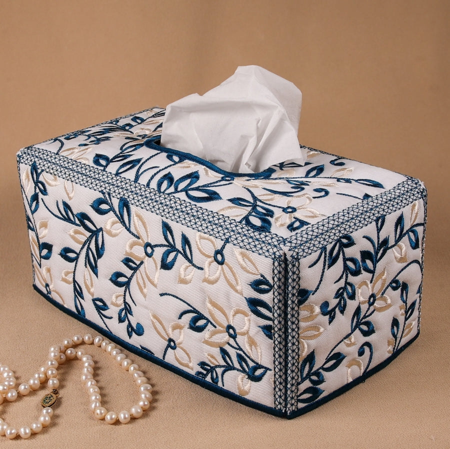 A rectangular tissue box cover with a floral machine embroidery design in blue and beige.