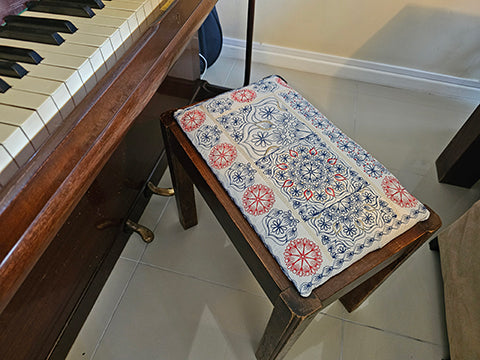 A quilt block with a geometric pattern featuring a combination of solid and quilted sections, predominantly in blue, red, and white.