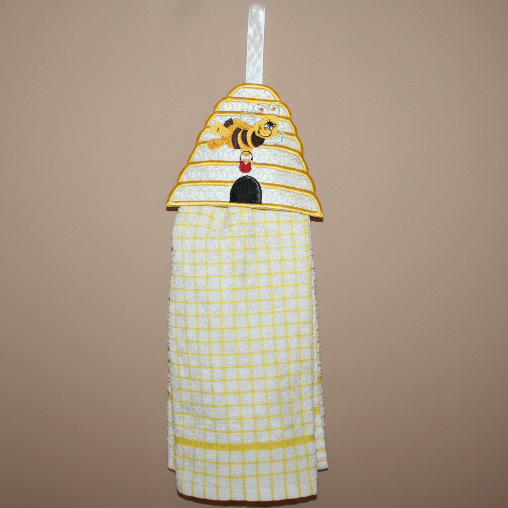 Kitchen towel with bee design hanging on a hook in a kitchen setting