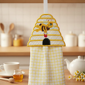 Kitchen towel with bee design hanging on a hook in a kitchen setting