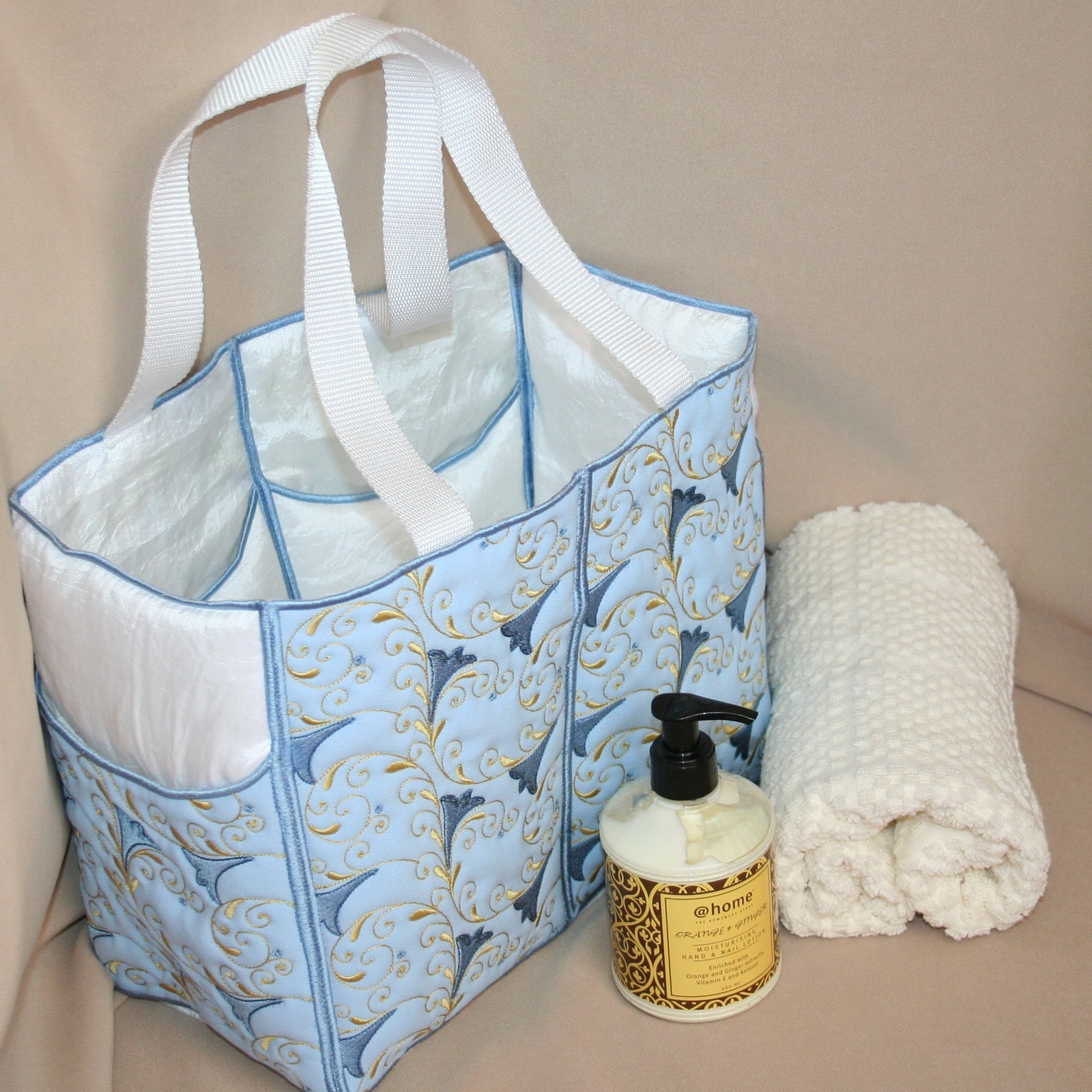 Blue patterned tote bag with a bottle of @home product on a beige surface
