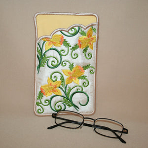 Floral embroidered case with a pair of glasses on a beige background