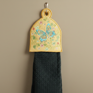 Decorative towel hook with butterfly design on a beige wall.