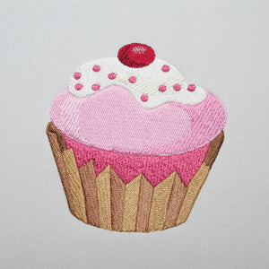 Embroidered patch of a cupcake with pink frosting and a red cherry on top.