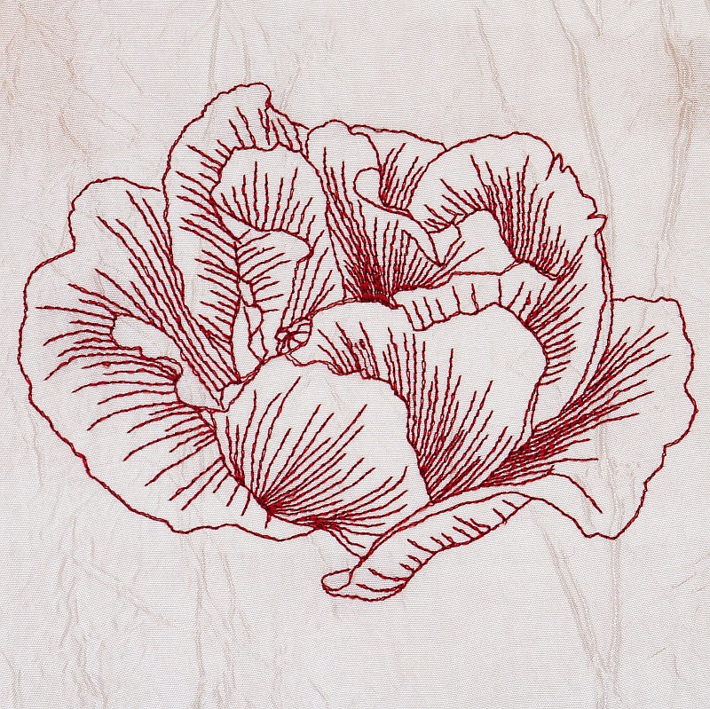 An off-white linen napkin with a red embroidered poppy flower by astitchahalf.net