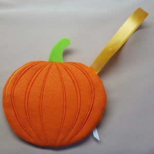 Orange felt pumpkin with a green stem and yellow leaf on a gray background