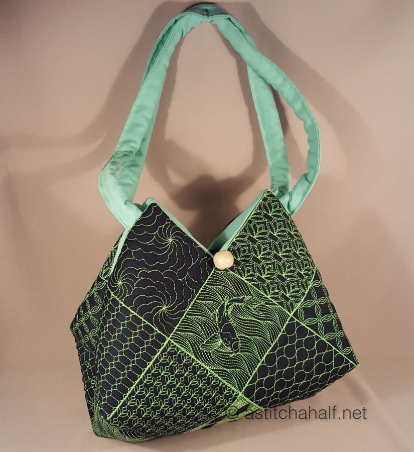 Green and black patterned handbag with a gold button on a beige background