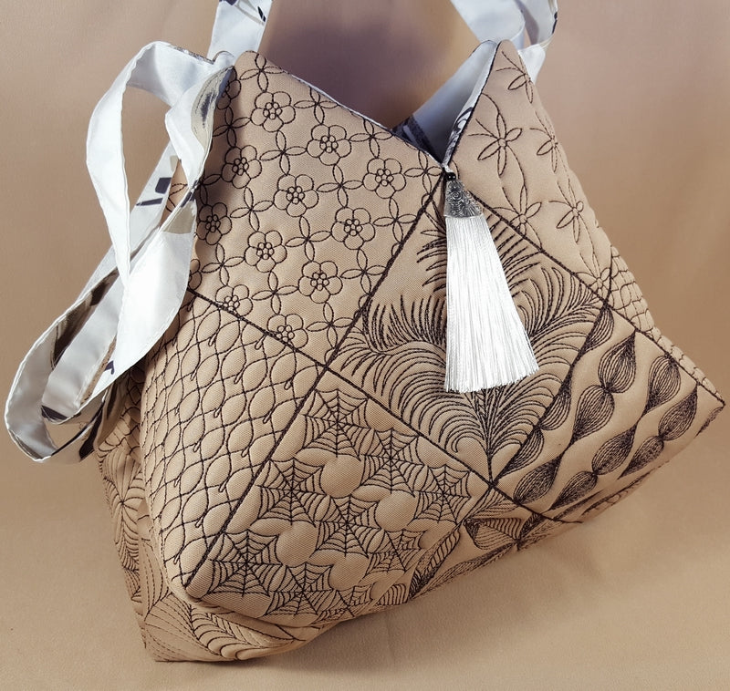 Beige handbag with floral patterns and a white tassel on a beige background