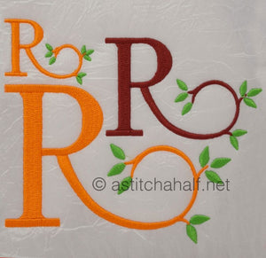 Embroidered letter 'R' in various colors with green leaves on a textured white background.