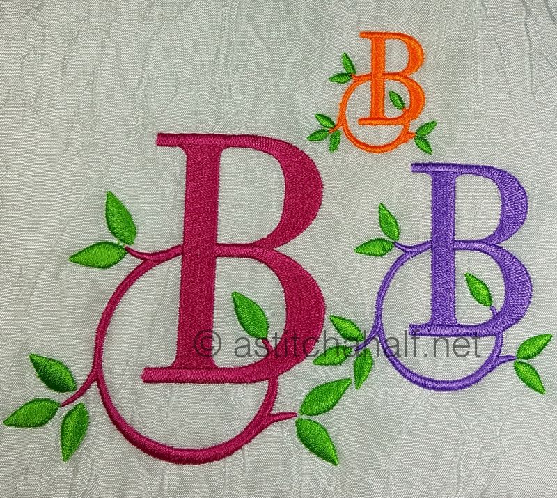 Embroidered letters 'B' in various colors with green leaves on a textured fabric background.