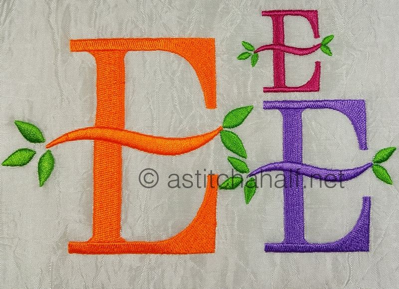 Embroidered letters 'E' in various colors with green leaves on a textured fabric background.