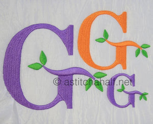 Embroidered letters 'G' in purple and orange with green leaves on a white background.
