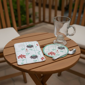 Embroidered placemat and coaster with floral design on a beige surface.