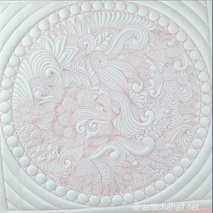 A close-up of a white quilted fabric featuring an intricate circular mandala pattern with light pink stitching details.