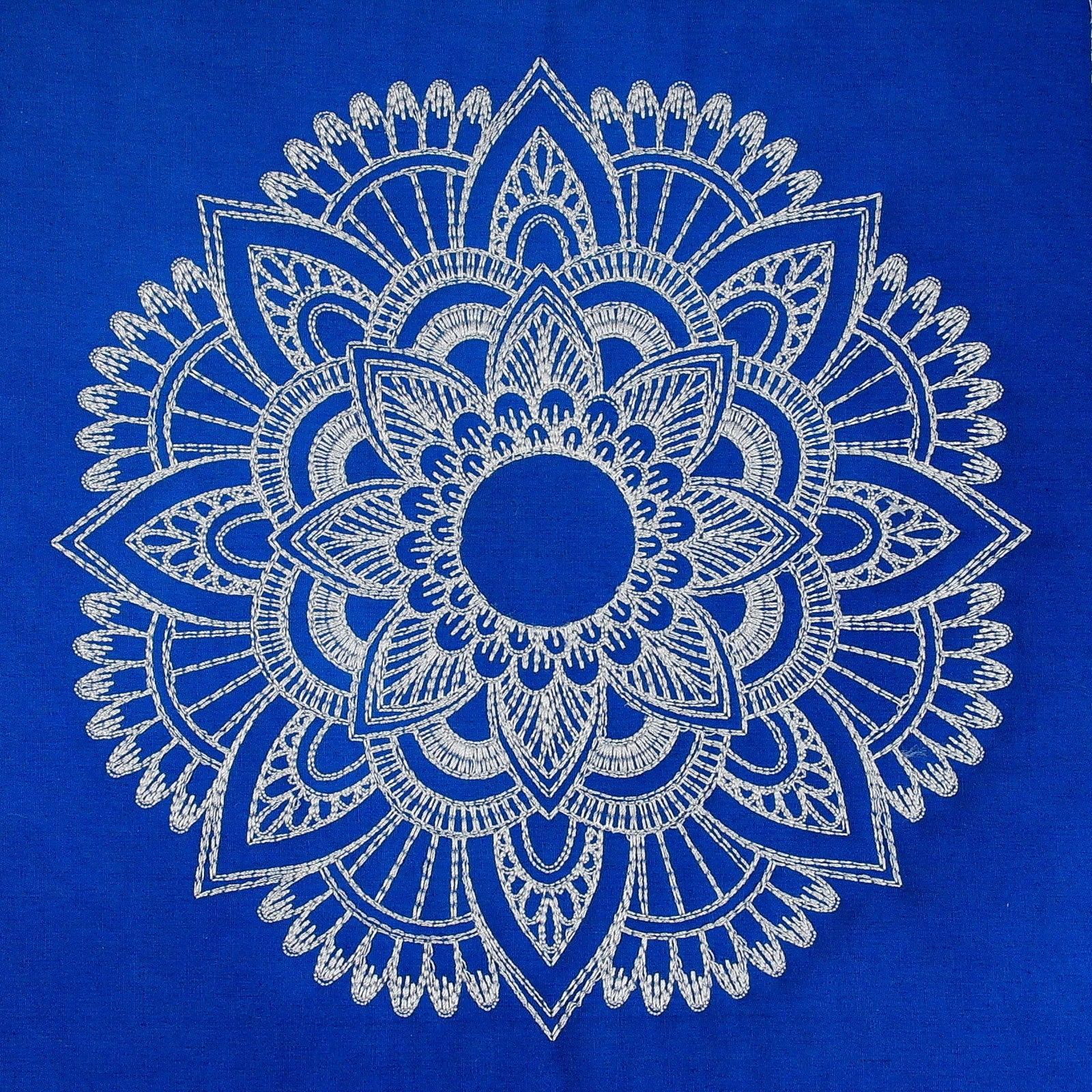 Blue mandala-patterned throw blanket on a bed with white bedding and pillows.