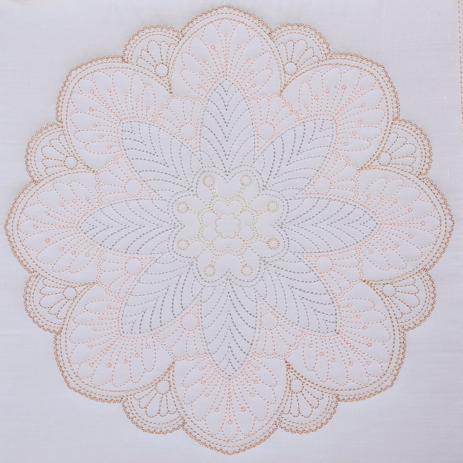 Embroidered white doily with a pink flower and clear glass container on a light wooden surface