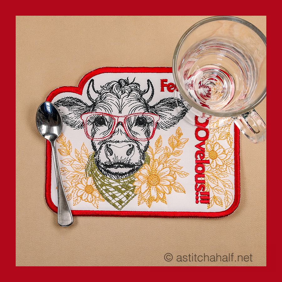 A fabric mug rug with the text 'Feeling Moovelous' and an illustration of a bull wearing glasses and a bandana, surrounded by floral designs.