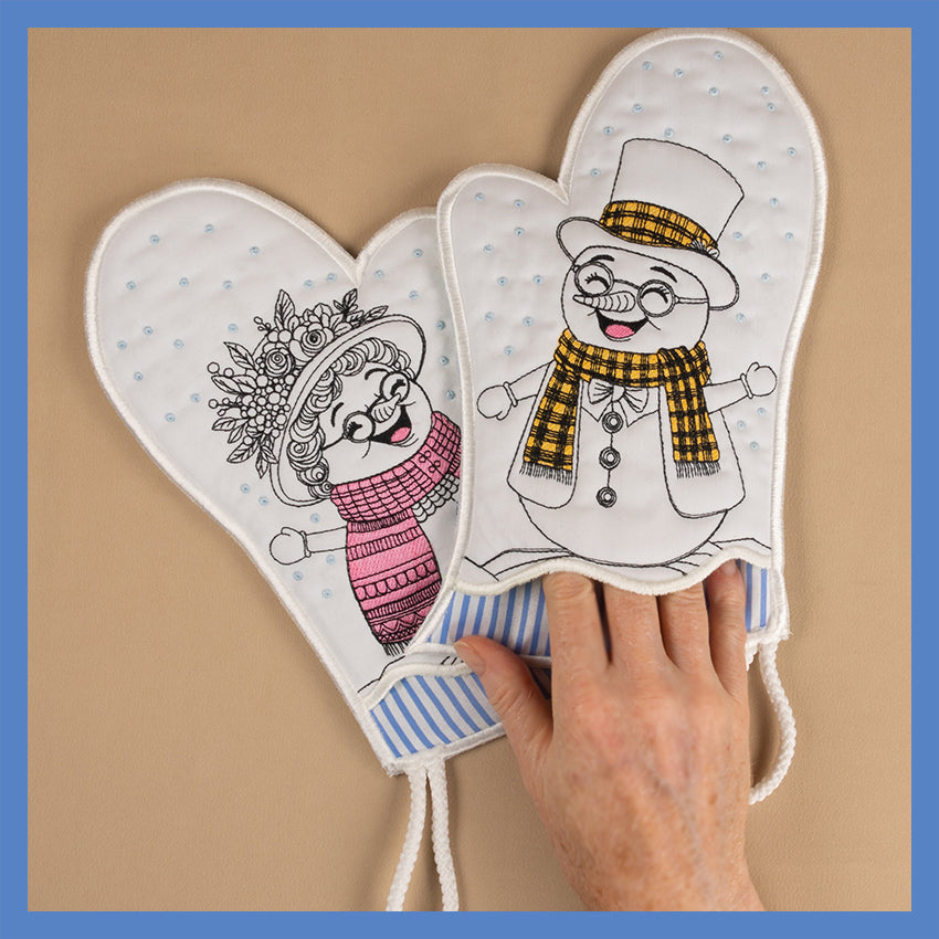 A pair of oven gloves featuring cartoon illustrations of a snowman and a snowwoman on a white background with blue stripes.
