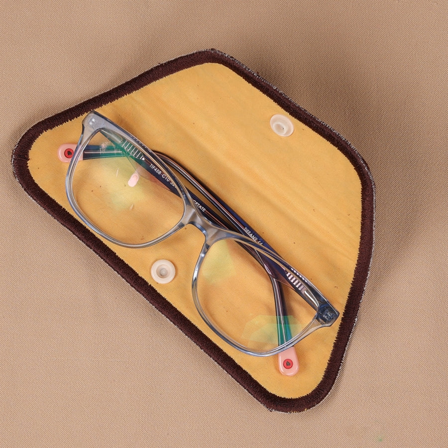 A hand holding an eyeglass sleeve with a geometric pattern, containing glasses with blue frames.