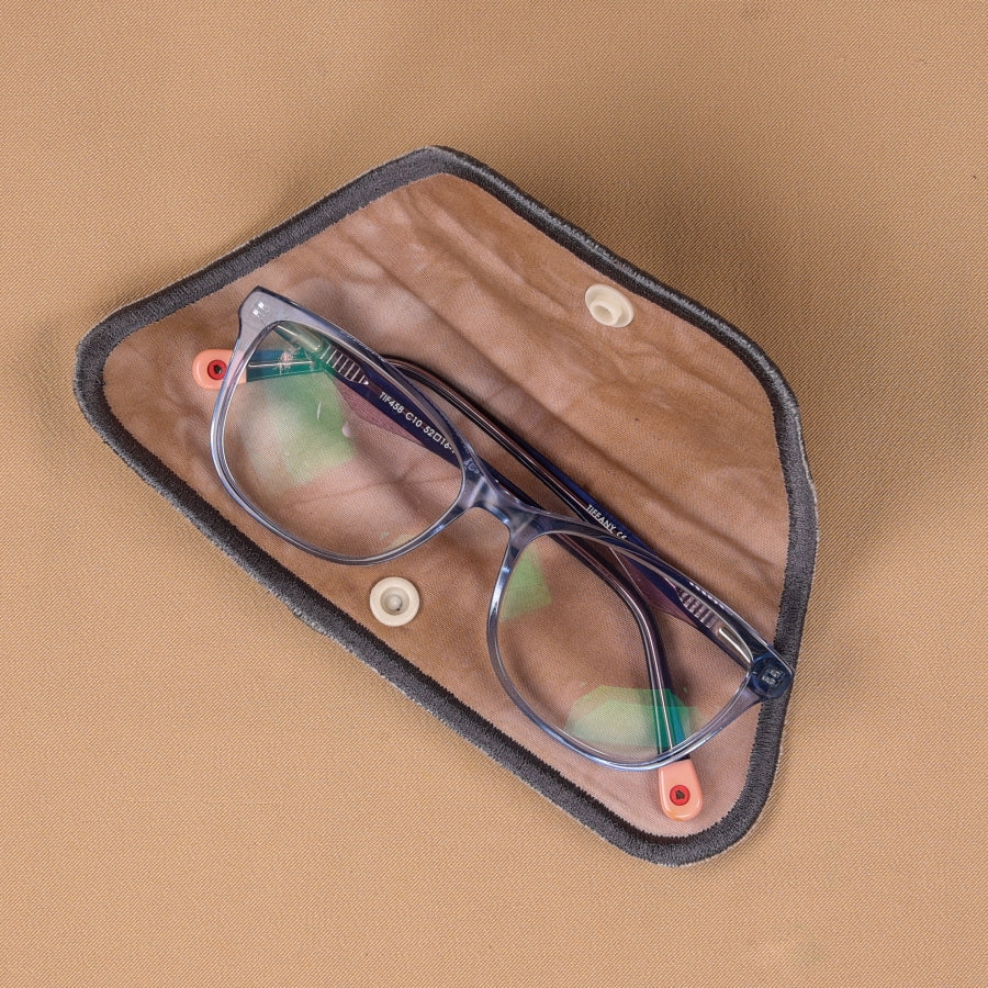 A hand holding a gray eyeglass sleeve with a leaf pattern and a blue elastic band.