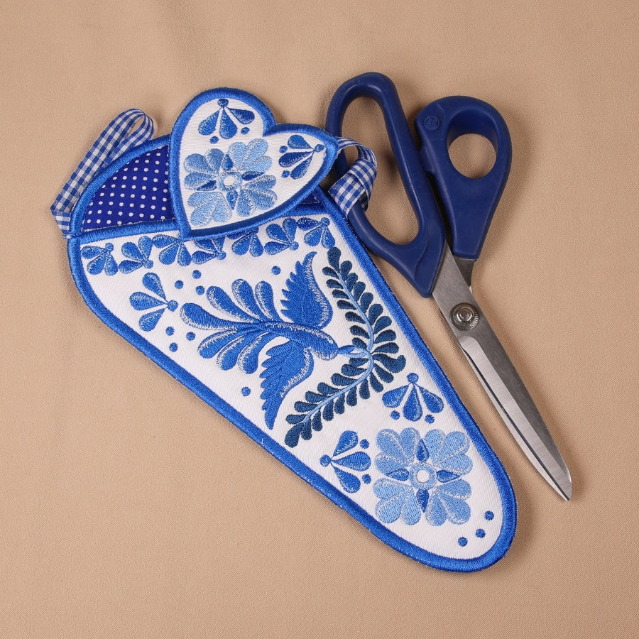 A completed embroidered scissor case with a geometric blue and white pattern alongside a pair of scissors.