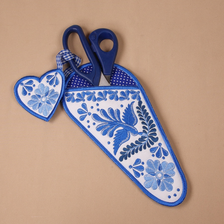 A completed embroidered scissor case with a geometric blue and white pattern alongside a pair of scissors.