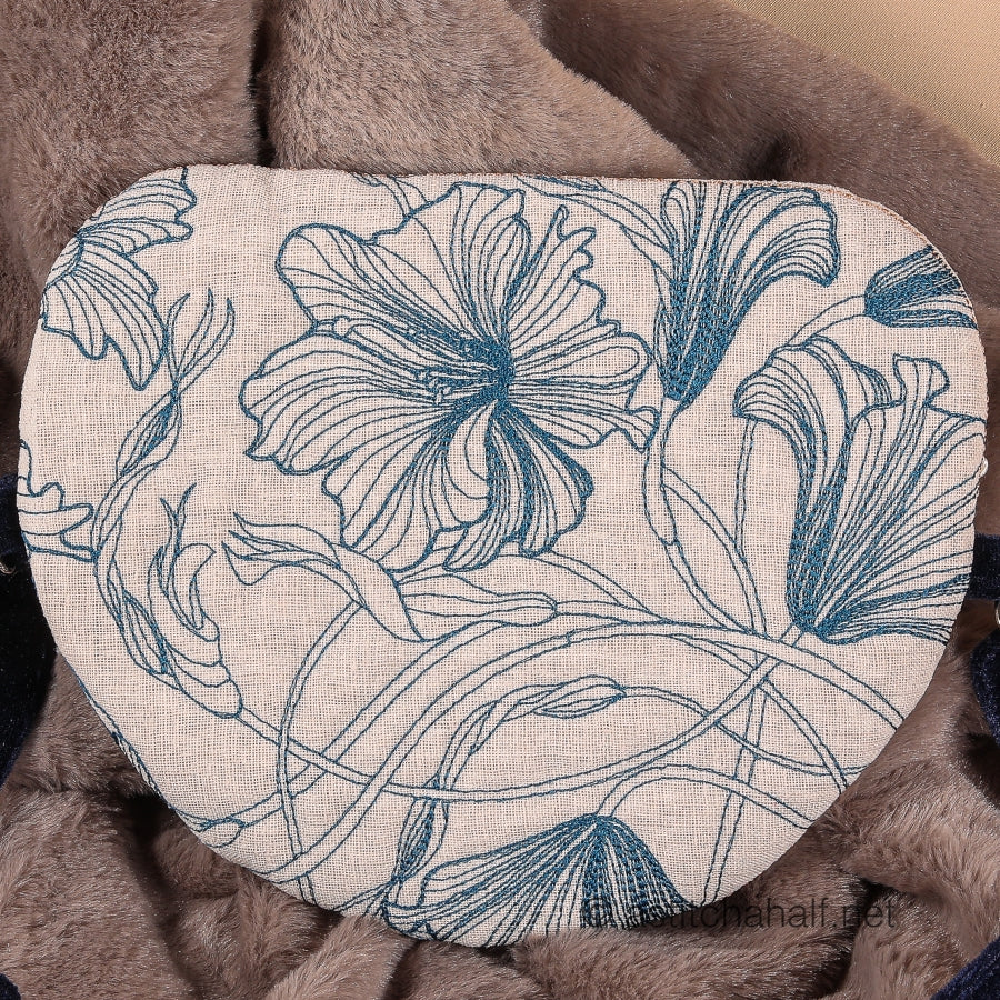 A completed zipper bag with a floral design, predominantly in blue and beige colors, laid on a soft, textured surface.