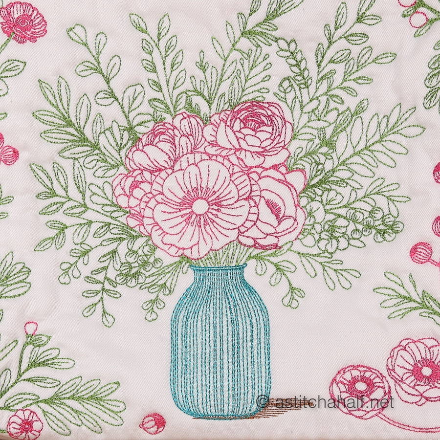 Embroidery pattern of a blue vase with pink flowers and green leaves on a white background.