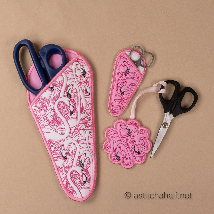 Scissors with pink flamingo patterned sheath and accessories on a beige background