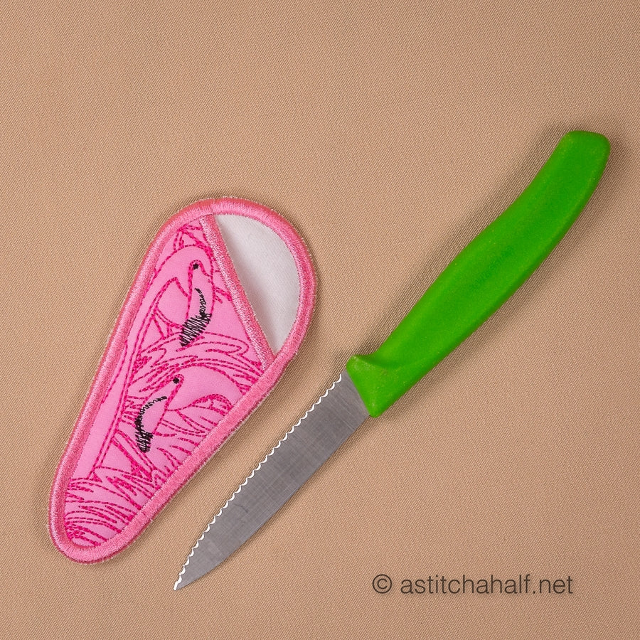 Scissors with pink flamingo patterned sheath and accessories on a beige background