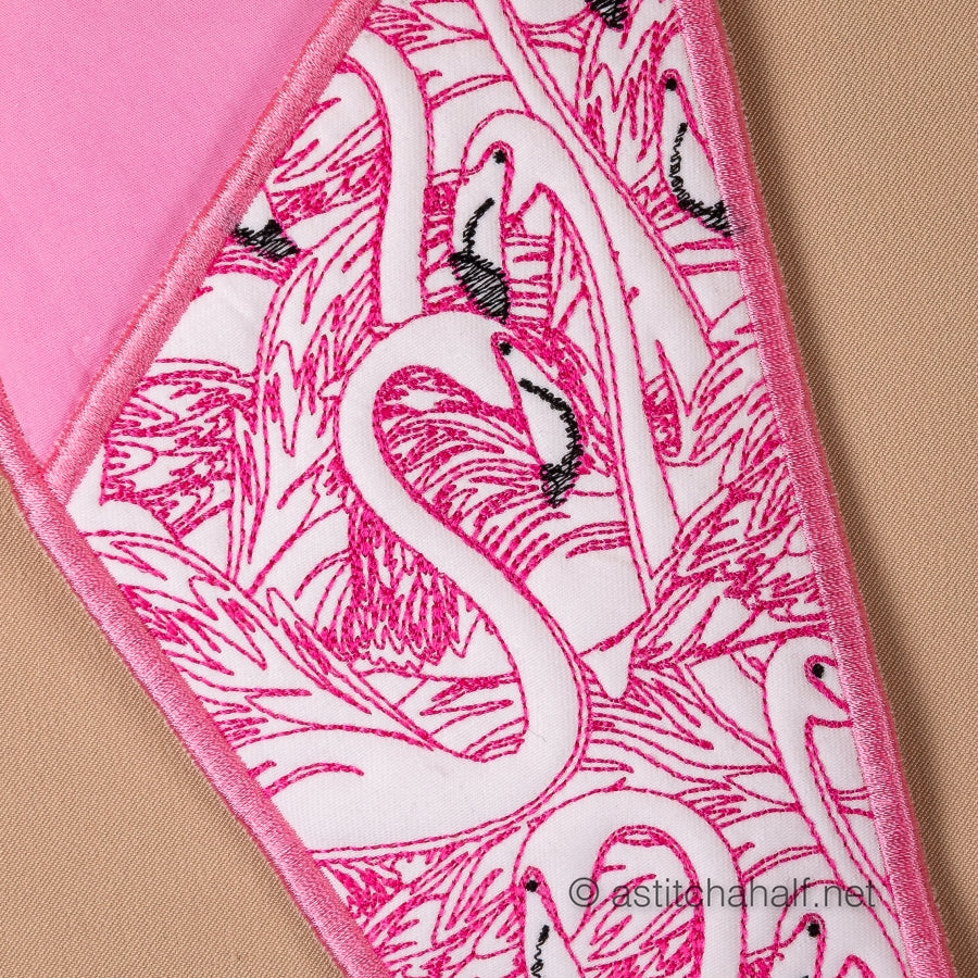 Scissors with pink flamingo patterned sheath and accessories on a beige background