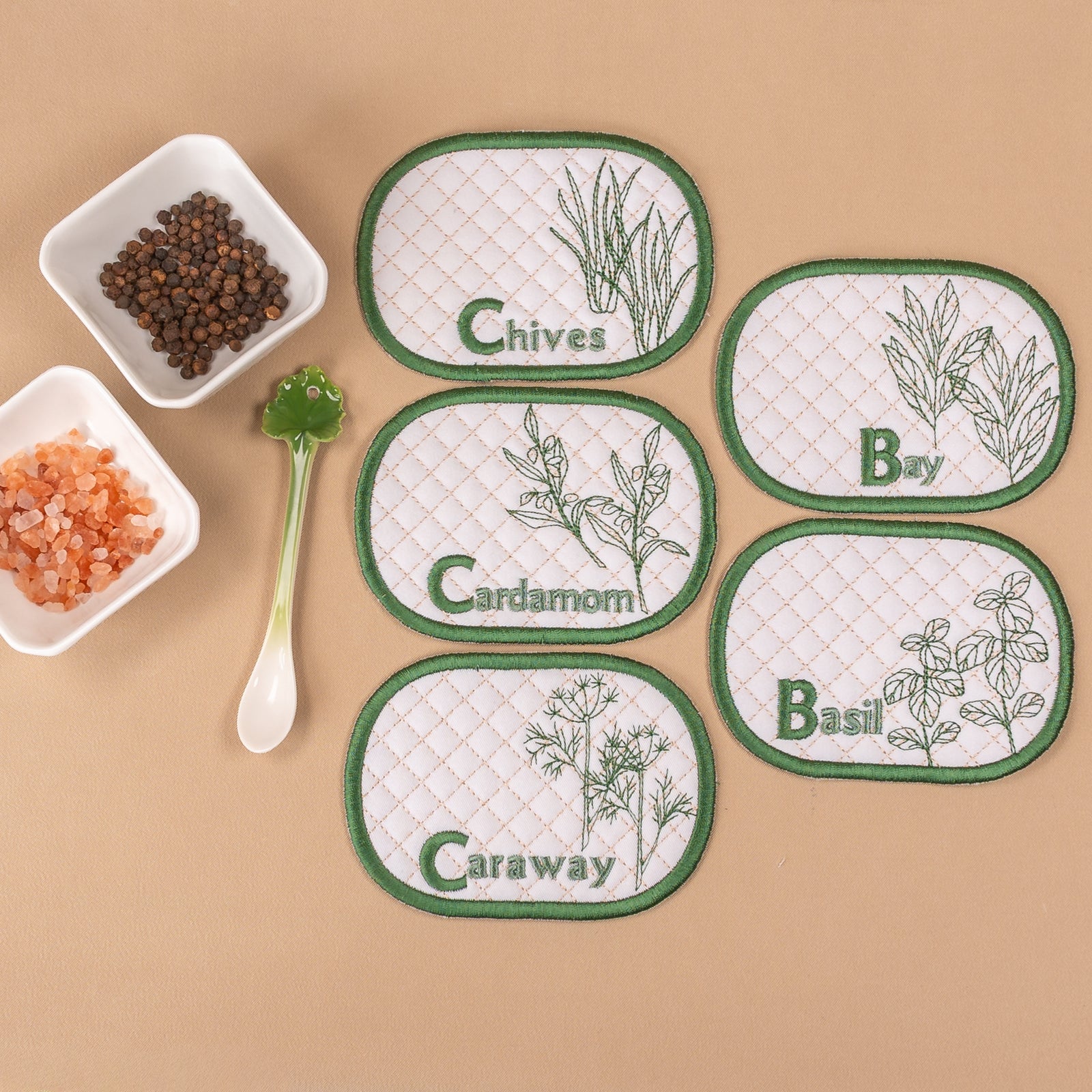 Set of herb-themed coasters on a beige background with small containers of spices.