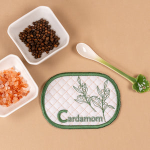 Patch with cardamom design and cardamom seeds on a beige background