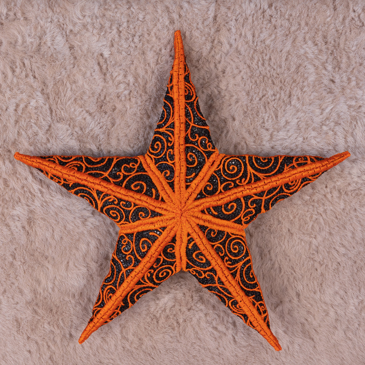 Decorative star with orange and black patterns on a textured beige background