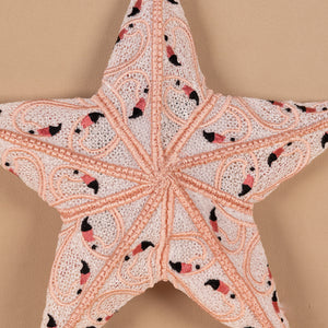 Star-shaped pillow with intricate patterns of flamingos on a beige background