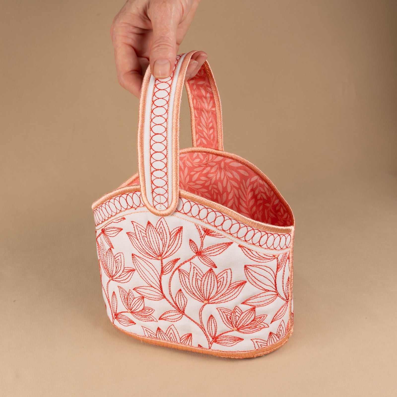 Fabric basket with floral embroidery on a beige background