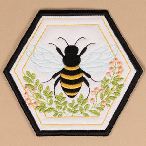 Embroidered patch of a bee and flowers on a beige background