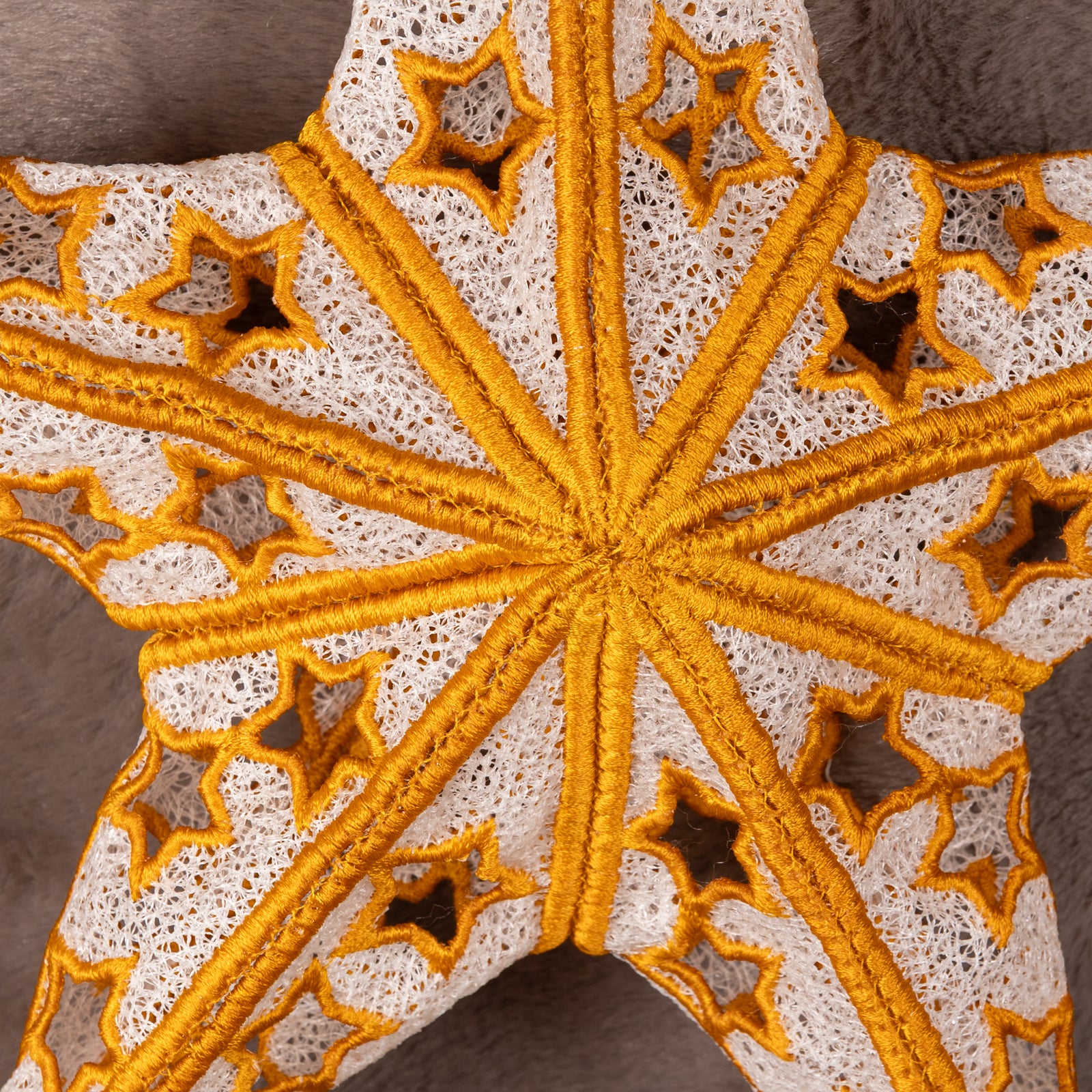 Decorative star ornament with gold and white pattern on a textured brown background