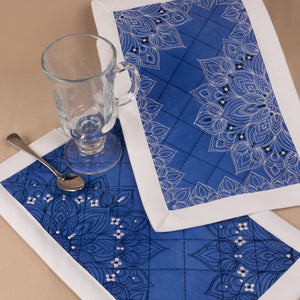 Blue placemats with white patterns on a beige surface