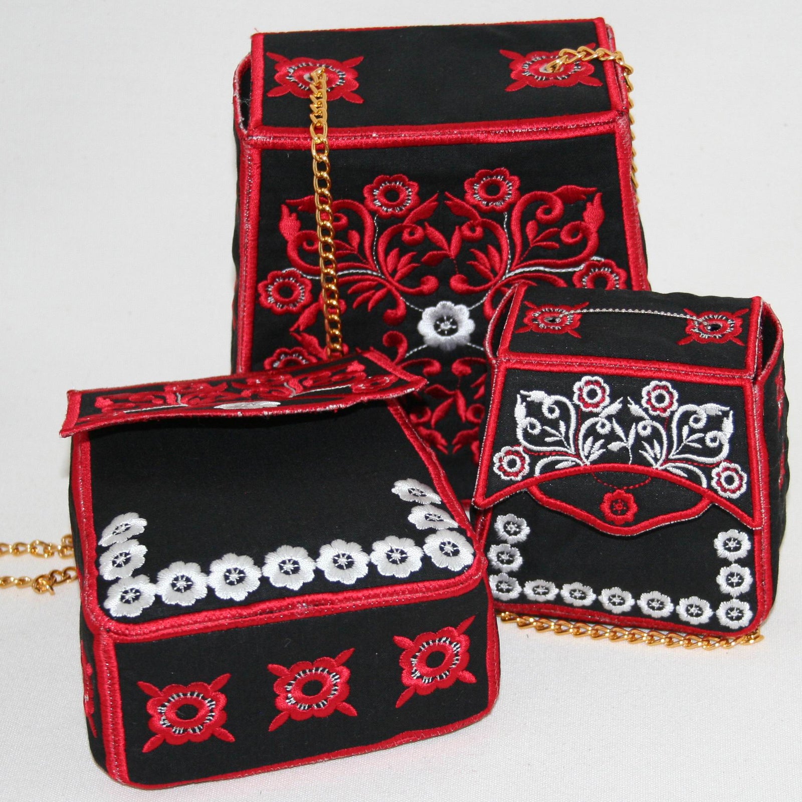 Three black handbags with red and white embroidery on a light gray background