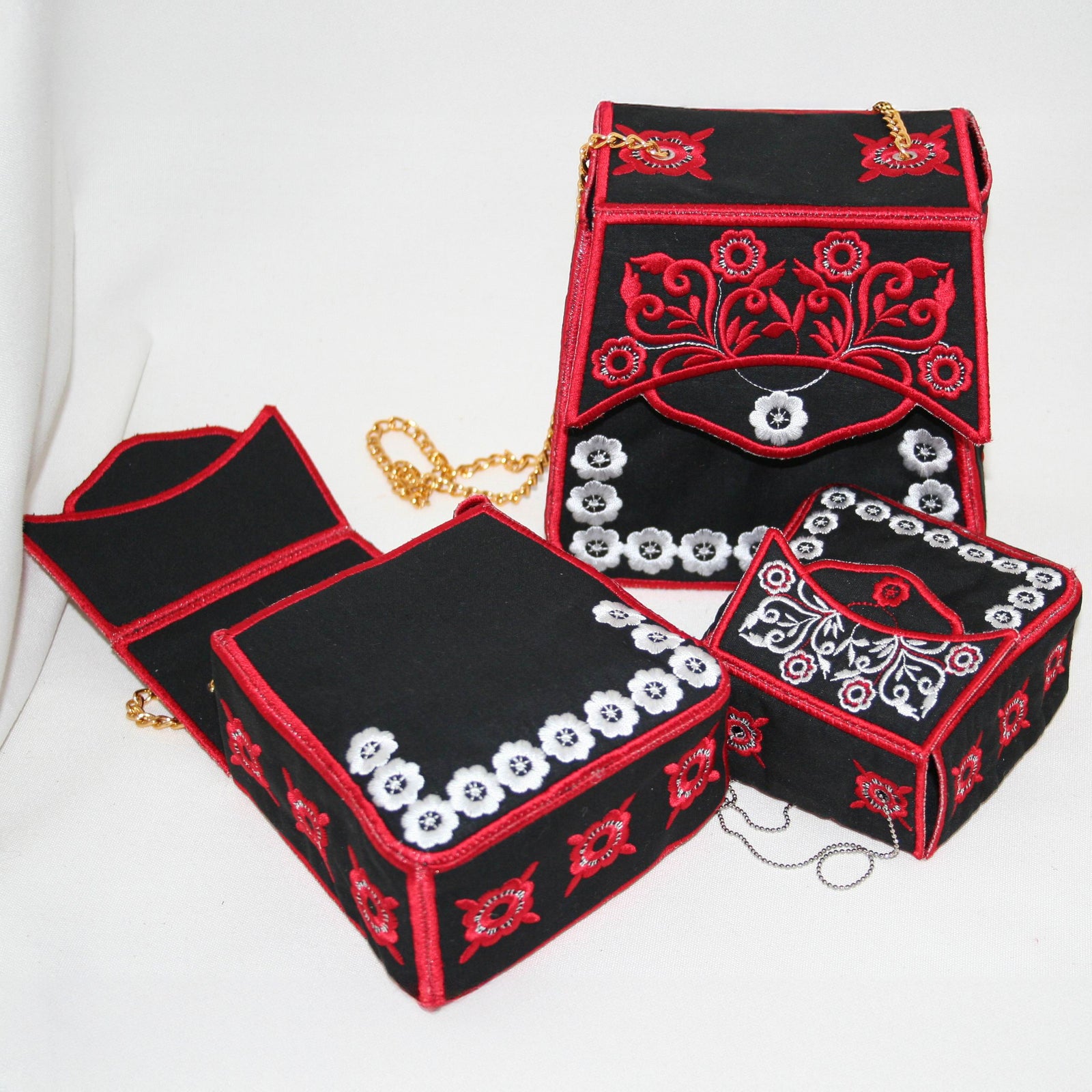 Three black handbags with red and white embroidery on a light gray background