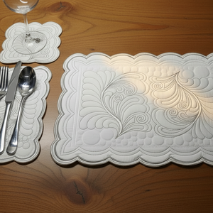 Decorative white placemats with intricate patterns on a wooden table.