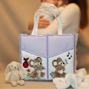 Baby bag with teddy bear design, woman holding a baby in the background