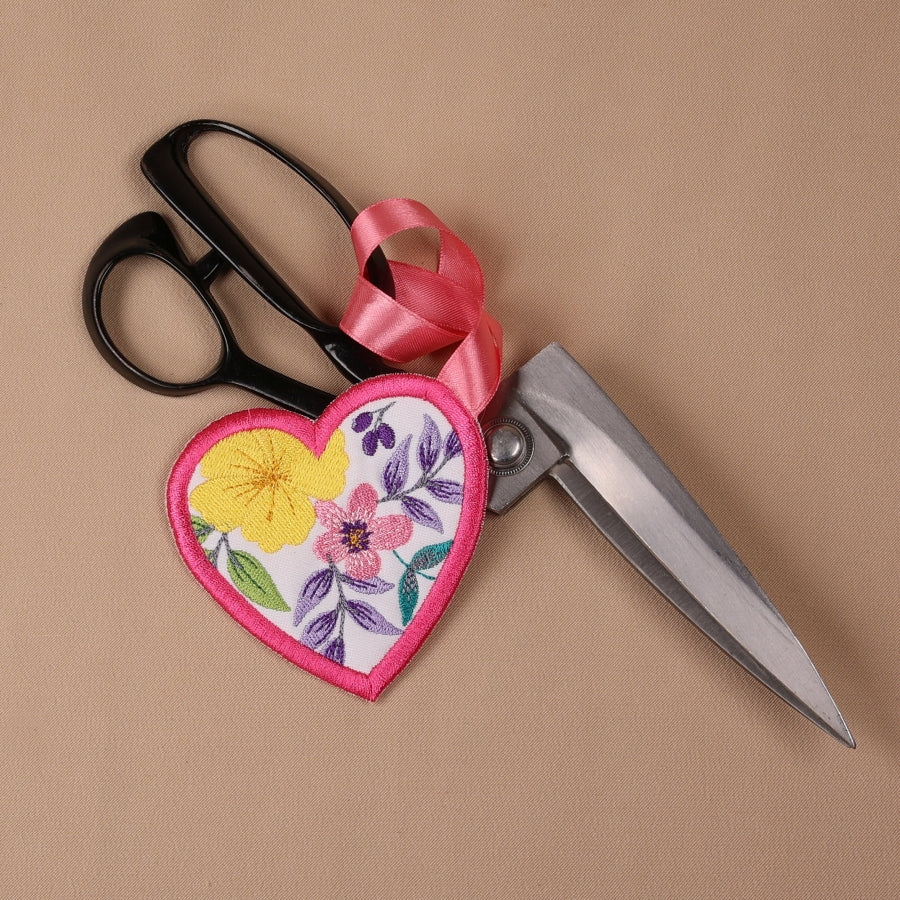 A floral fabric scissor case and fob set with a pink ribbon.