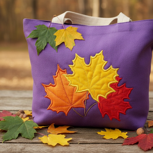 Purple tote bag with colorful leaf appliqués on a wooden surface with autumn leaves.