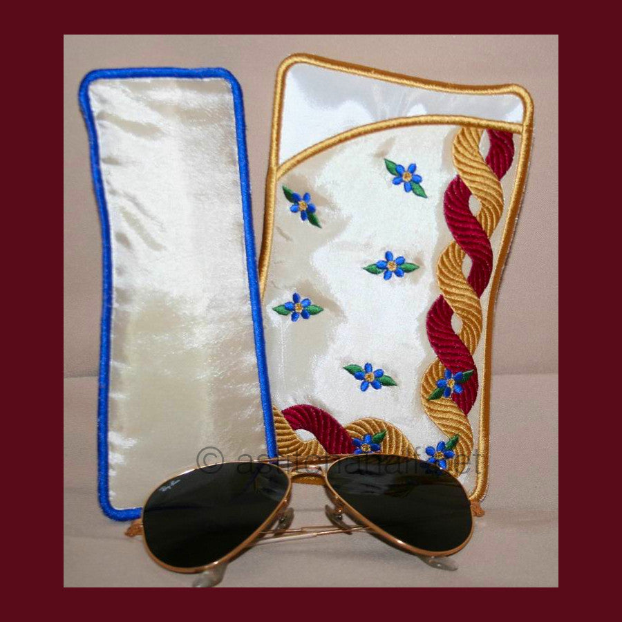 Royal Eyeglass Cases 05 - aStitch aHalf. Two embroidered eyeglass cases with decorative braided trim patterns in red and gold, along with small blue flowers - one with gold binding and one with blue binding.