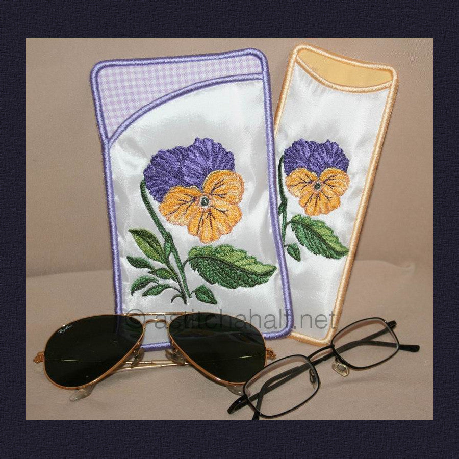 Pansy Eyeglass Cases - a-stitch-a-half. Two embroidered eyeglass cases featuring purple and yellow pansy flowers with green leaves - one with purple gingham trim and one with yellow trim.