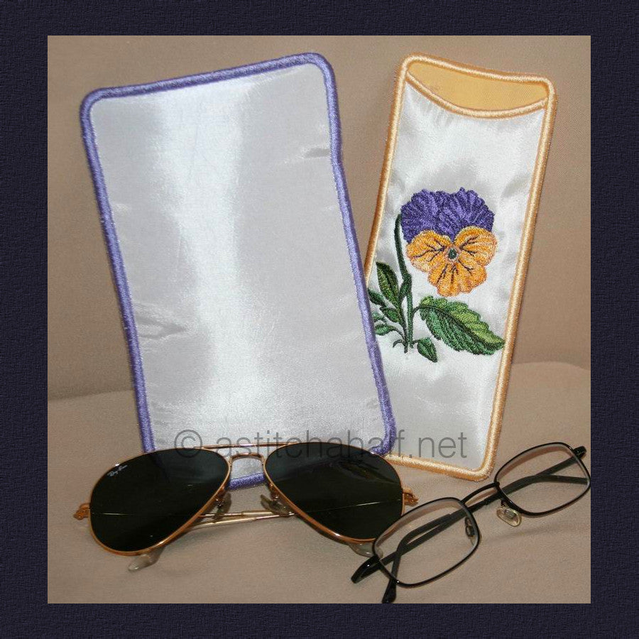 Pansy Eyeglass Cases - a-stitch-a-half. Two embroidered eyeglass cases featuring purple and yellow pansy flowers with green leaves - one with purple gingham trim and one with yellow trim.