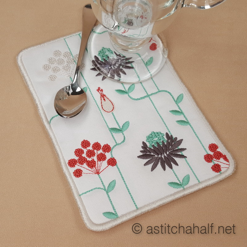 Embroidered placemat and coaster with floral design on a beige surface.